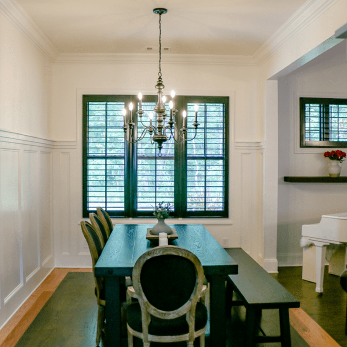 Dark interior movable louvered shutters built by Dwell Shutter & Blinds displayed in a dining room.