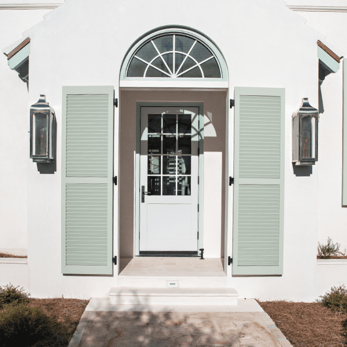 Louvered Exterior Shutters built by Dwell Shutter & Blinds attached the front corridor of a coastal home.