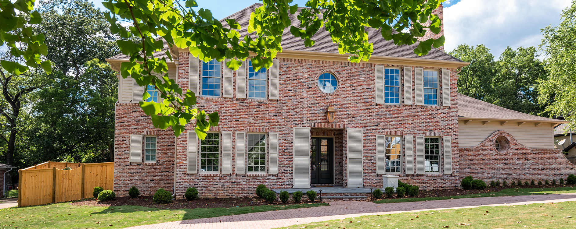 Louvered exterior shutters built by Dwell Shutter & Blinds displayed on every window and entryway of a home.